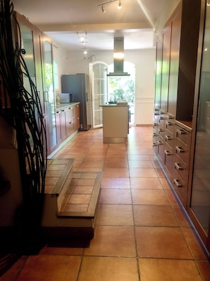 A modern kitchen with a central island, cabinets, and a sliding glass door leading to a balcony. - Mansion - Correns (Correns)