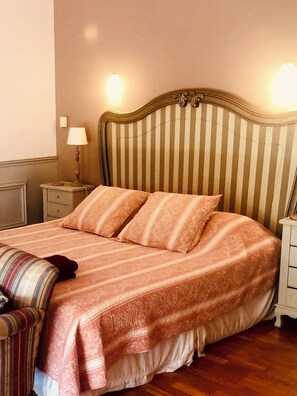 A bed with a striped headboard, a bedside lamp, and a striped throw blanket. - Mansion - Correns (Correns)