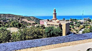 A coastal town with a prominent mosque featuring a tall minaret, surrounded by greenery and buildings. - Superb F2 Apartment With INCREDIBLE Panoramic View (Souk El Ténine)