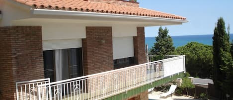 Una casa de dos plantas con balcón, piscina y vista al mar.