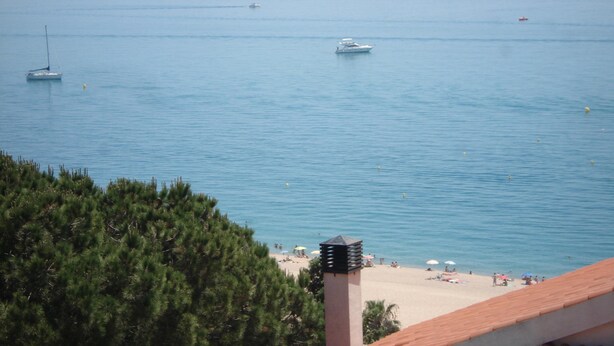 Blick auf die Küste mit Strand, Booten und blauem Himmel.