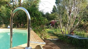 A swimming pool with a wooden deck and metal railings, surrounded by lush greenery and trees. - Shed renovated with charm, swimming pool and bucolic garden at the foot of the Luberon (Cheval-Blanc)