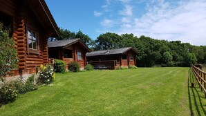 Eine Blockhütte mit einem Rasen und einem Holzzaun.