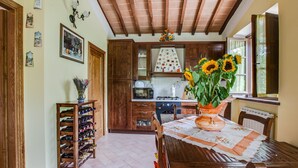 Una cocina con armarios de madera, una mesa de comedor con mantel floral y un jarrón de girasoles.