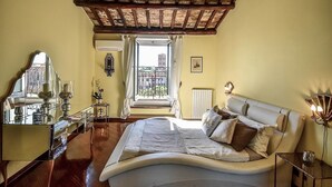 Una camera da letto con un letto grande, uno specchio, un comò e una finestra con vista su un edificio.