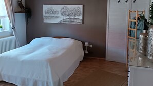 A bedroom with a bed, a bedside table, a lamp, a wardrobe, and a painting on the wall. - Cozy vacation home for up to 8 pers., 4 bathrooms, W- Lan, sauna house, dog allowed  (Trendelburg)