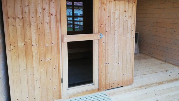 A wooden sauna with a door and a thermostat on the wall. - Cozy vacation home for up to 8 pers., 4 bathrooms, W- Lan, sauna house, dog allowed  (Trendelburg)