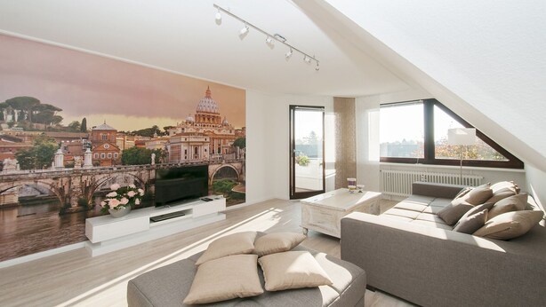 A modern living room with a large mural of a cityscape, a comfortable sofa, a flat-screen TV, and a dining area with a white table. - Best location 5 stars from DTV conveniently located luxury new (Hamburg-Halstenbek)