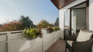 A balcony with potted plants, a wicker chair, and a glass door leading to an interior space. - Best location 5 stars from DTV conveniently located luxury new (Hamburg-Halstenbek)