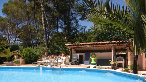 Una piscina con sillas de descanso y una zona pequeña cubierta con una silla y una mesa.