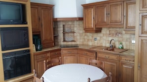 Een keuken met houten kastjes, een magnetron, een koffiezetapparaat en een spoelbak.