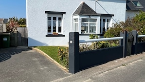 A two-story house with a white exterior, a black roof, and a gated entrance.