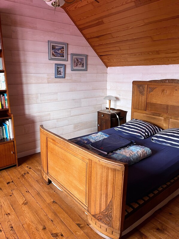 A bedroom with a wooden bed, a nightstand, a lamp, and a bookshelf.