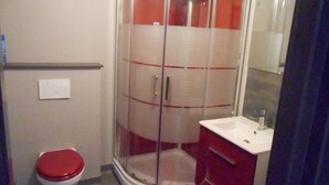 A bathroom with a toilet, a shower enclosure, and a sink. - duplex apartment bis (Vannes)