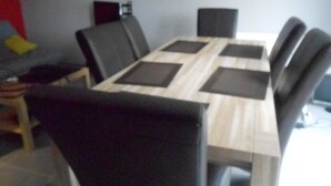 A dining area with a rectangular table, black chairs, and a grey sofa. - duplex apartment bis (Vannes)