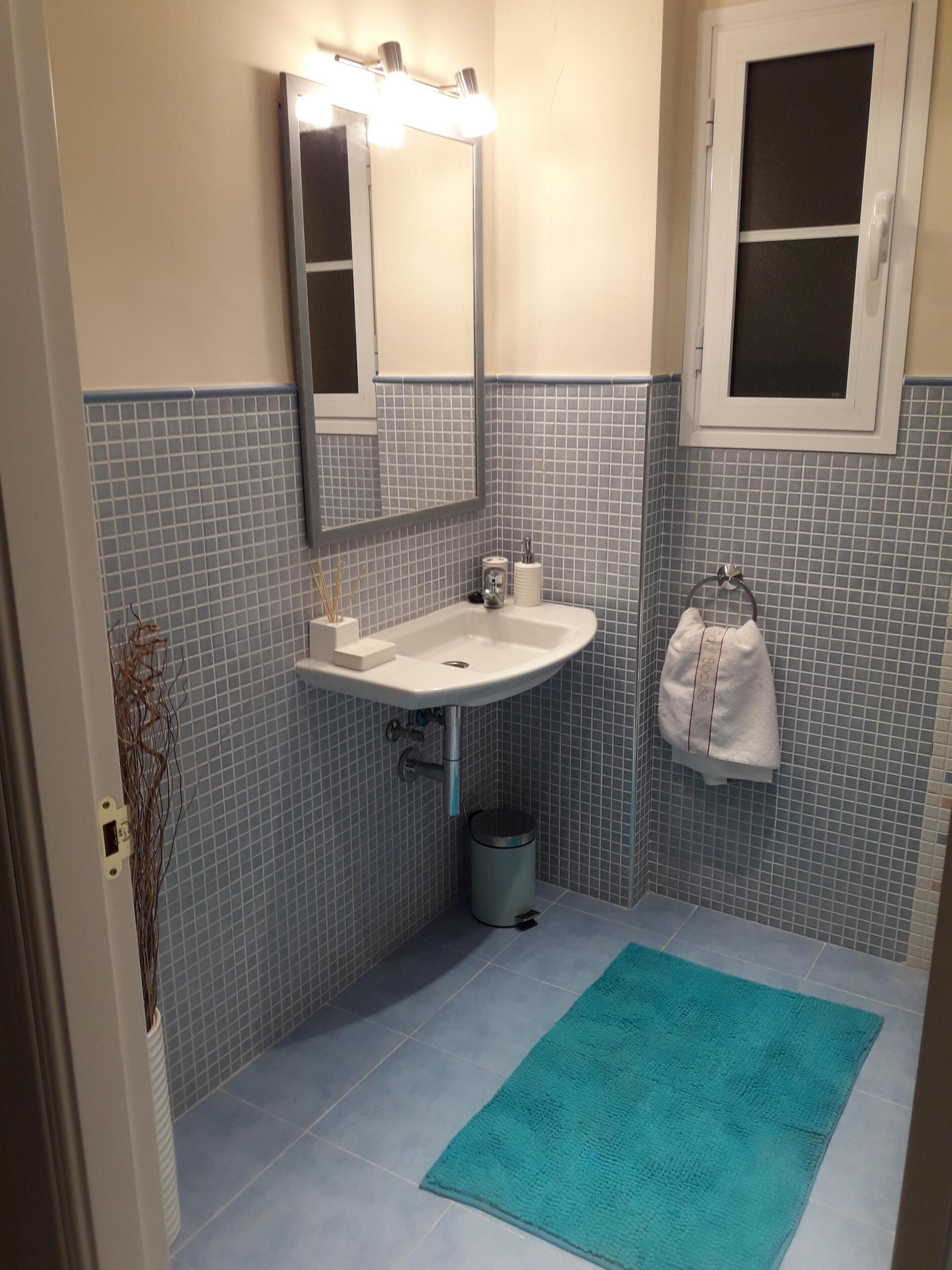 A bathroom with a sink, mirror, and towel rack.