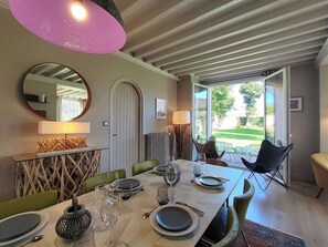 A dining area with a table set for four, a large mirror, and a view of the outdoors. - Villa Le Petit Bois - 2 mns walk Sword beach -Large enclosed garden - Car park (Hermanville-Sur-Mer)