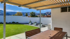 A covered patio with a table and chairs, a grassy lawn, and potted plants. -  5 bdrm, 3.5 bth Private Luxury retreat with mountain views! Permit #068365 (La Quinta)