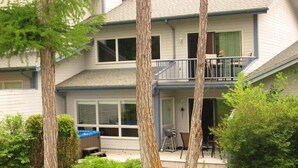 Ein zweistöckiges Haus mit einem Balkon, einer Veranda und einem kleinen Grillbereich im Freien.