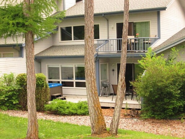 Een tweelaags huis met een balkon, een overdekte veranda en een klein barbecuegedeelte.