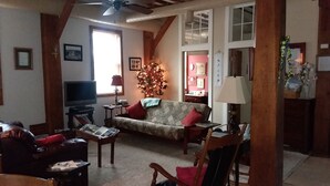 Una sala de estar acogedora con un sofá, sillones, una mesa de centro y un televisor.
