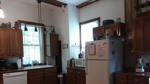 Una cocina con armarios de madera, un refrigerador blanco, un microondas y una cafetera.