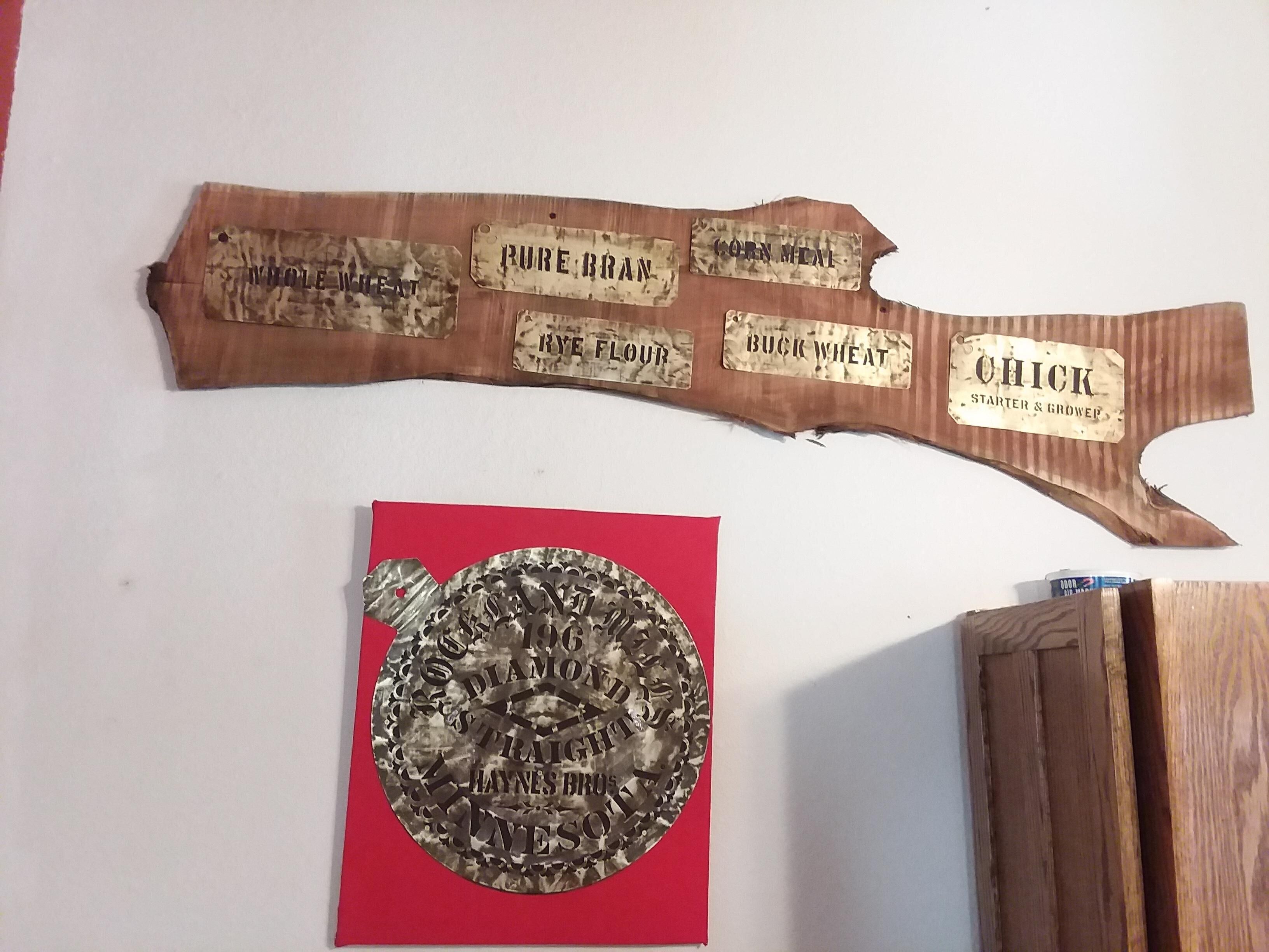 A wooden plaque with grain labels and a circular metal plaque with text.