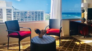 Une pièce avec deux chaises, une petite table et une vue sur l’océan.