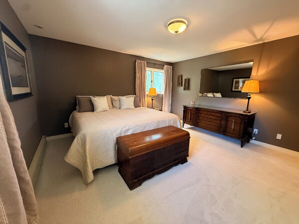 A bedroom with a bed, a dresser, a bench, a mirror, and a ceiling light.