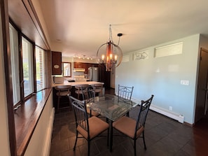 Una cocina moderna con una isla central, taburetes de bar y una mesa de comedor de cristal.