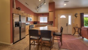 A modern kitchen with a central island, stainless steel appliances, and wooden cabinetry. - In Town Near Main Street!  Single Level With Garage - Private Gated Yard (Moab)