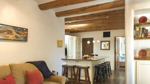 Ein gemütliches Wohnzimmer mit einer Couch, einem Couchtisch und einer Küchenzeile mit Barhocker und Arbeitsfläche.