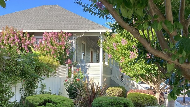 A well-maintained garden with a stone pathway leading to a house with a porch.