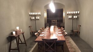 A long dining table with chairs, candles, and a wine rack in the background.