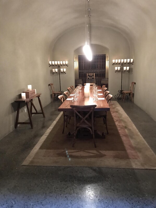 A long dining table with chairs, candles, and a wine rack in the background.