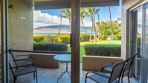 A balcony with a view of a golf course, palm trees, and a mountain in the distance. - Gorgeous Oceanfront Condo Steps From The Beach, Air Conditioned, Free Wi-Fi (Kihei)