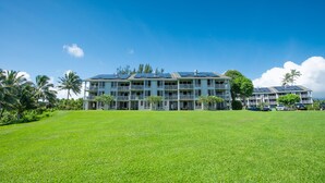 A multi-story hotel with a flat roof, solar panels, and a large grassy lawn. - Very Private location. Amazing View. The Cliffs 6302, 1 Vehicle Parking Included (Princeville)