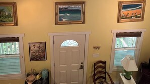 A room with a ceiling fan, a door with a stained glass window, and three framed pictures on the wall.