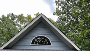 A house with a gabled roof, a front porch with a white picket fence, and a front door with a decorative glass panel.