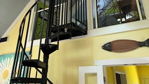 A multi-level interior with a spiral staircase, a ceiling fan, and a decorative fish sculpture.