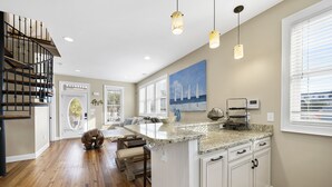 Una cocina amplia con una isla grande, suelo de madera e iluminación colgante.