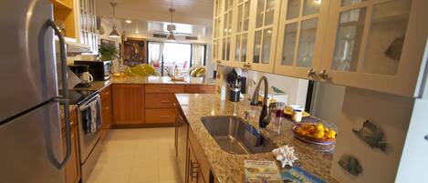 A kitchen with granite countertops, stainless steel appliances, and white cabinetry.