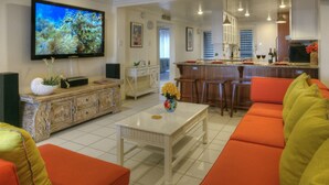 A living room with a television, orange sofa, and a white coffee table.