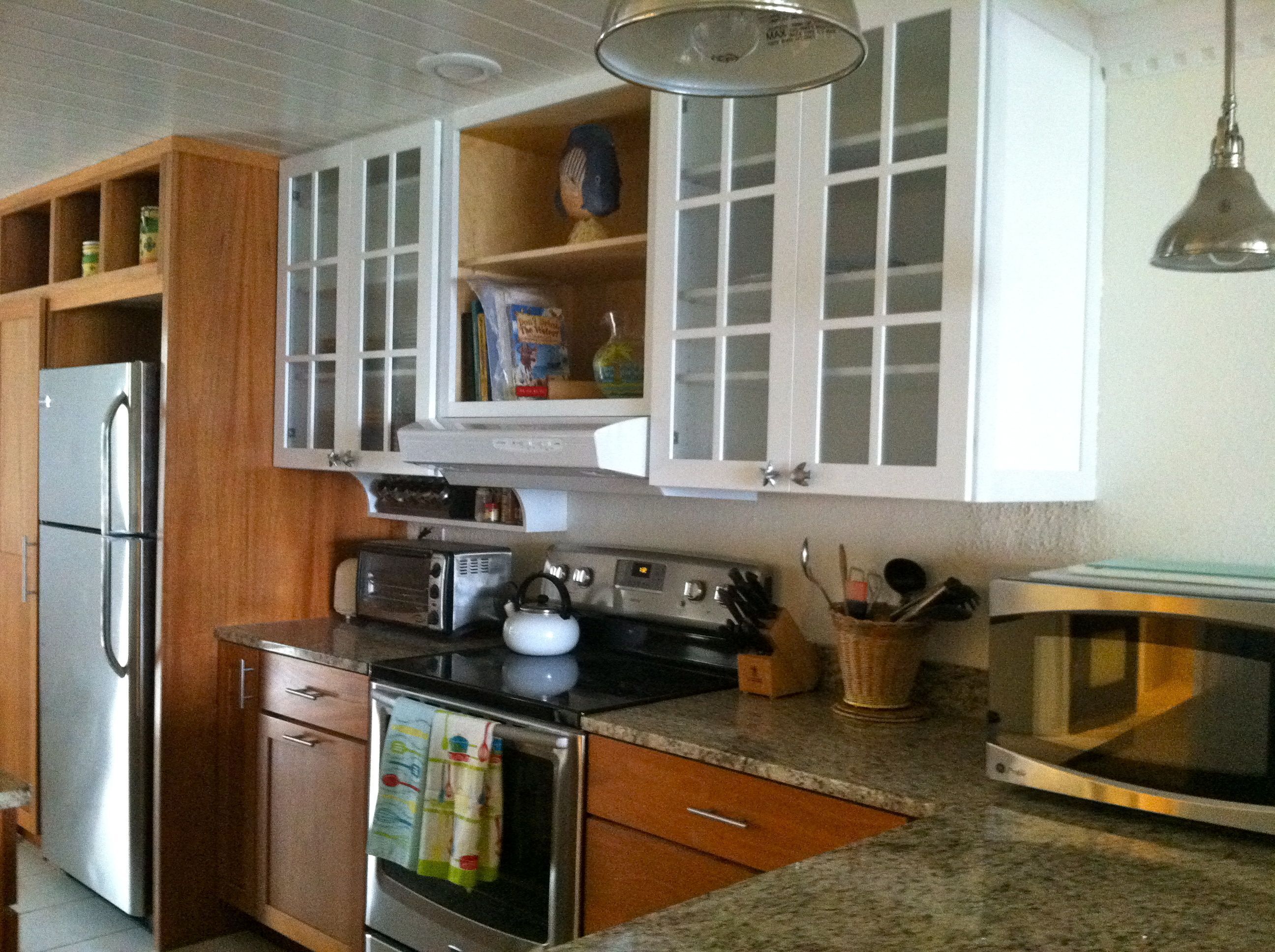 A kitchen with wooden cabinets, a refrigerator, a stove, a microwave, and a toaster.