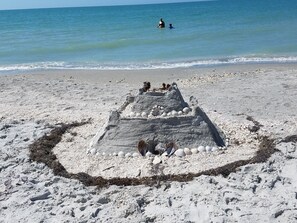 A sandy beach with a large sandcastle featuring a circular base and a pyramid-like structure. - SNOW BIRDS WELCOME! SUNSHINE AND  HEATED POOL (Cape Coral)