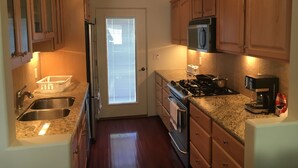 Una cocina compacta con armarios de madera, un lavamanos de acero inoxidable, una estufa y un microondas.