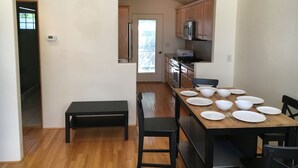 Una cocina moderna con armarios de madera, horno empotrado y comedor con una mesa de madera dispuesta para seis personas.