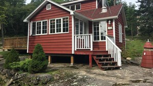A red house with white trim, a chimney, and a number '154' sign. - Muskoka Cottage Living  (Huntsville)