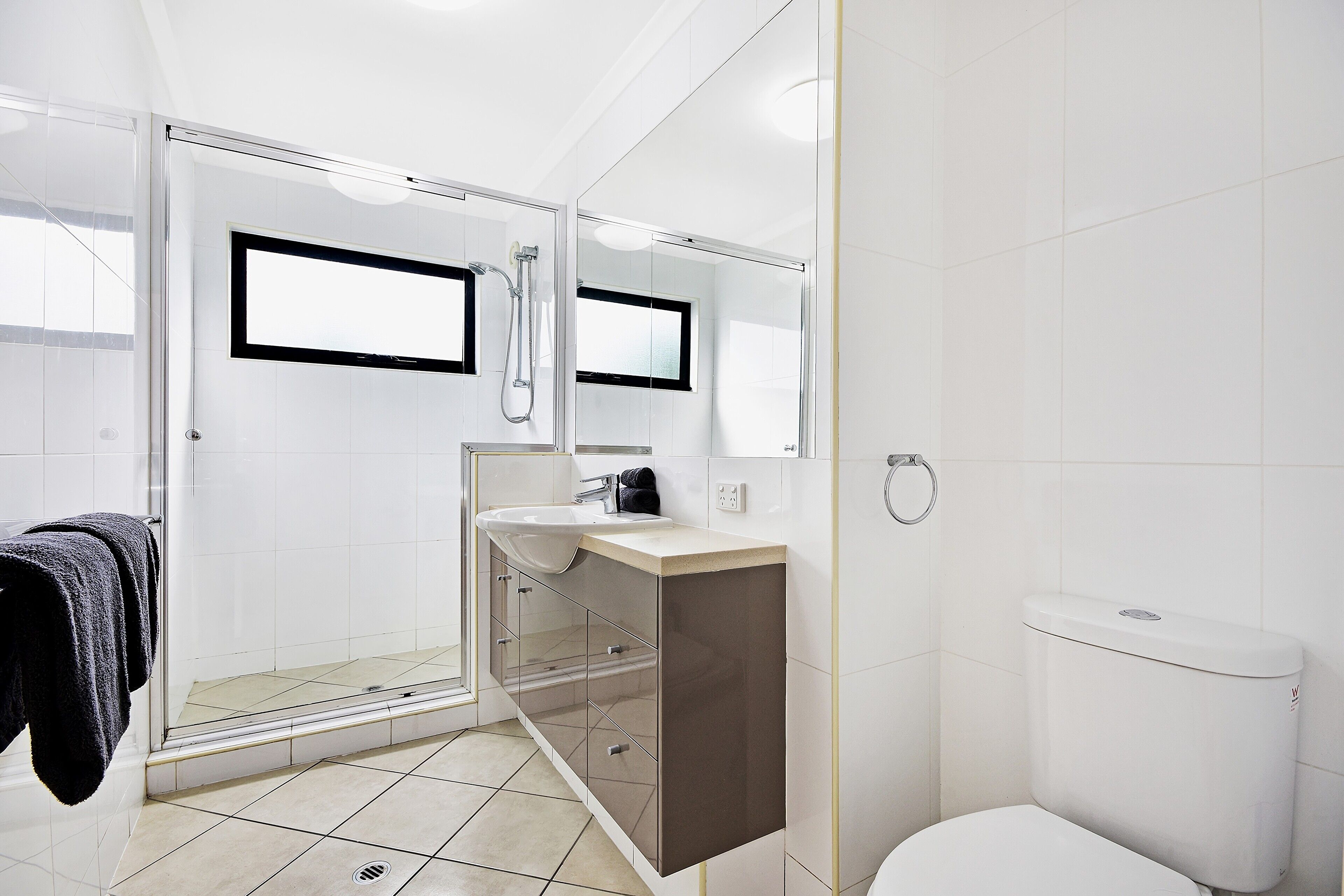 Un baño moderno con cabina de ducha de vidrio, un lavamanos con espejo y un inodoro.