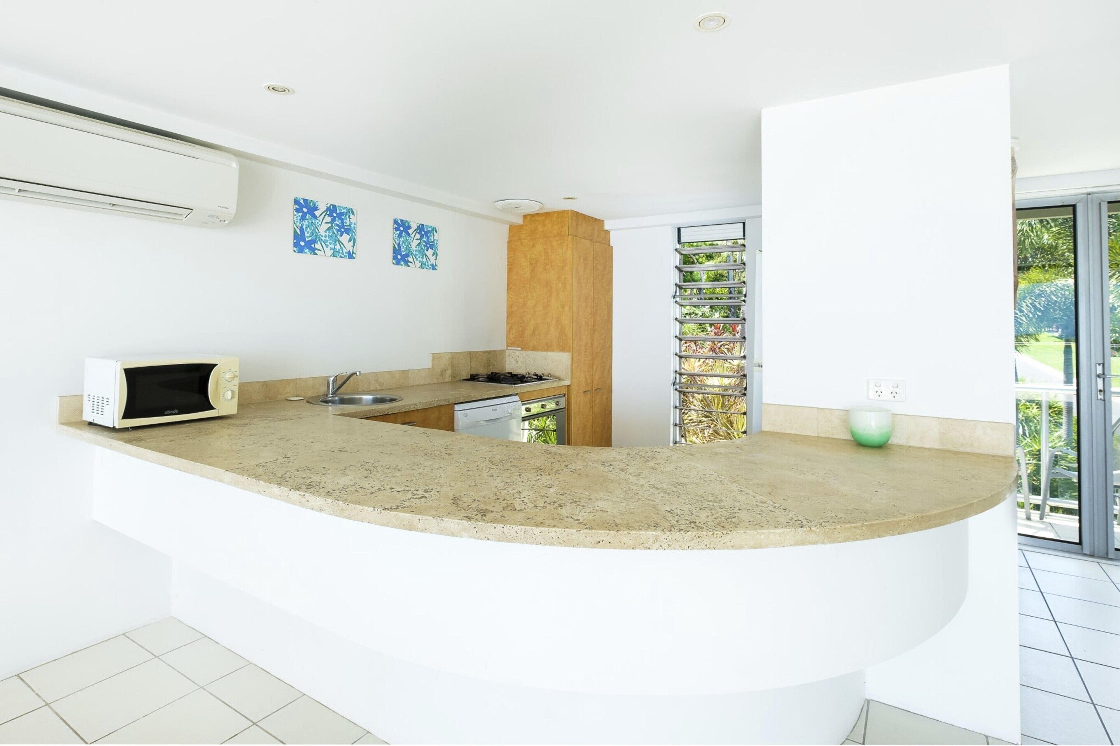 Una cocina moderna con una isla curva, electrodomésticos integrados y vistas a zonas verdes.